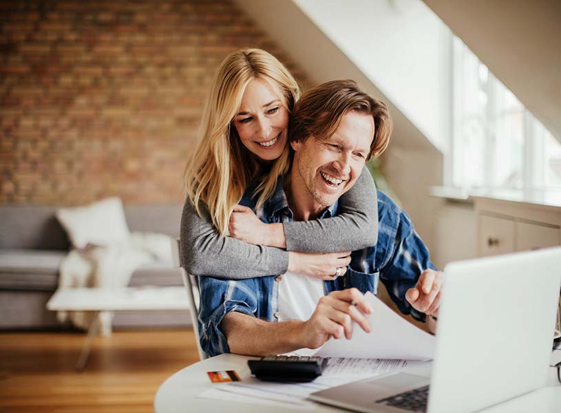 A husband and wife looking at financials on a laptop computer